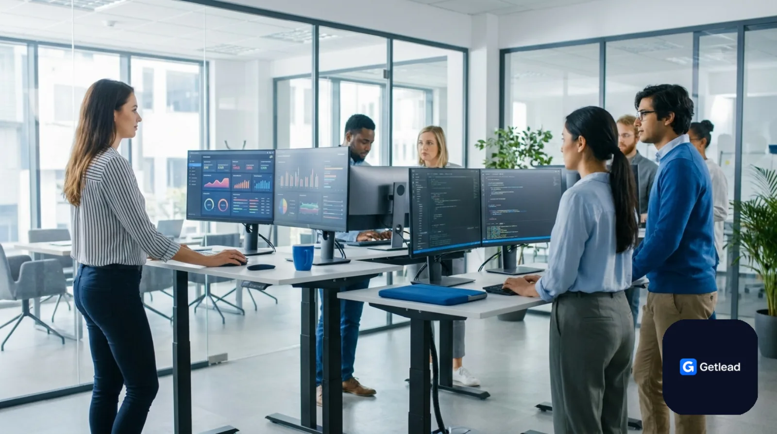 SaaS startup team at standing desks with dashboards on monitors