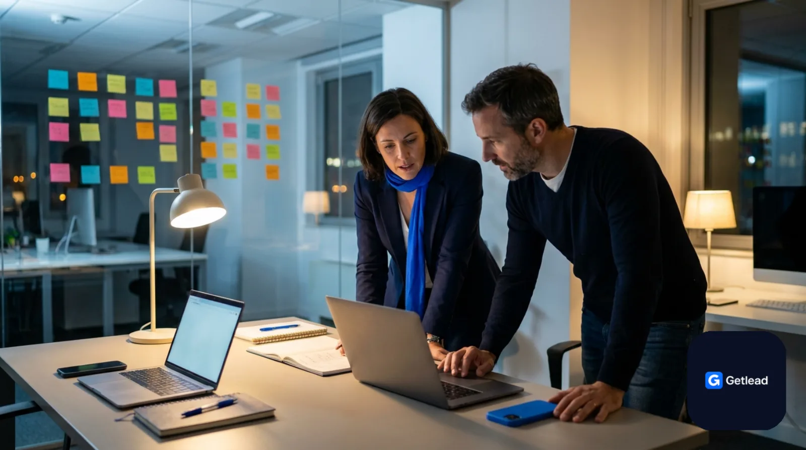 Two startup founders working late with sticky notes on a glass wall